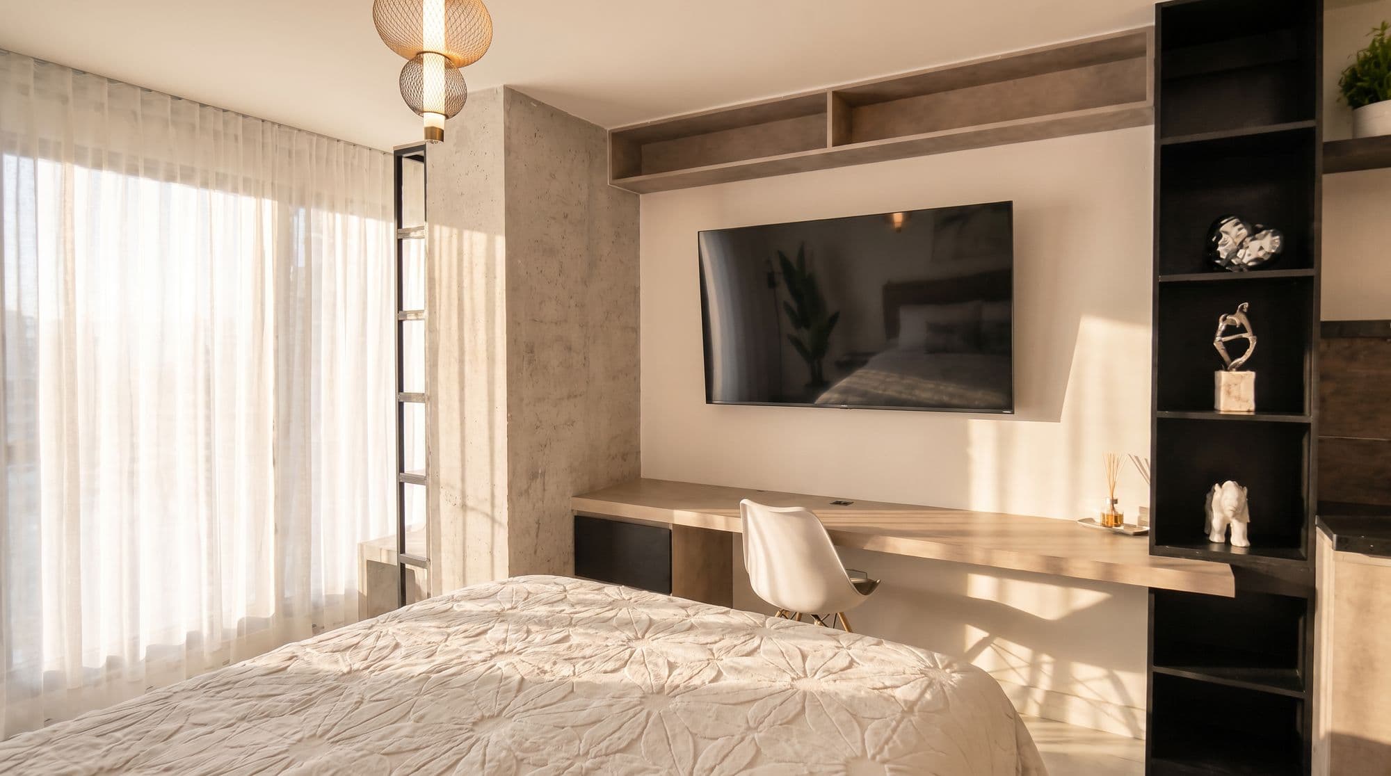 Habitación con escritorio de madera, estantería negra y columna de concreto