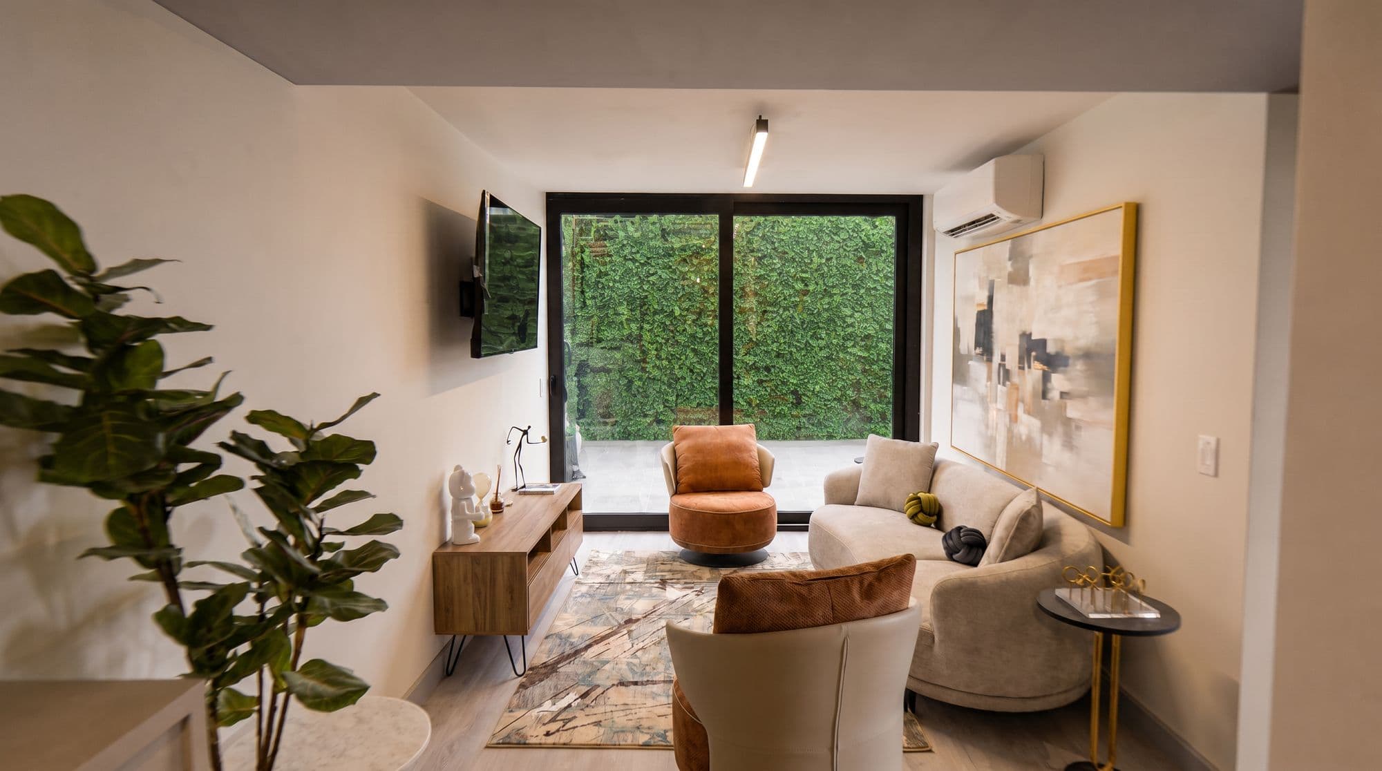 Sala con ventanal al jardín vertical y butaca coral