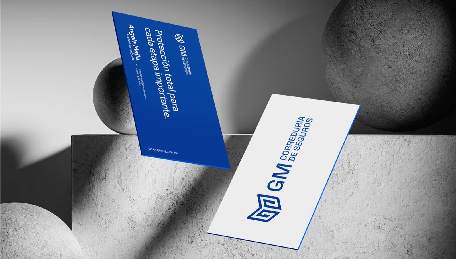 Tarjetas de presentación de GM Correduría de Seguros sobre una superficie de concreto