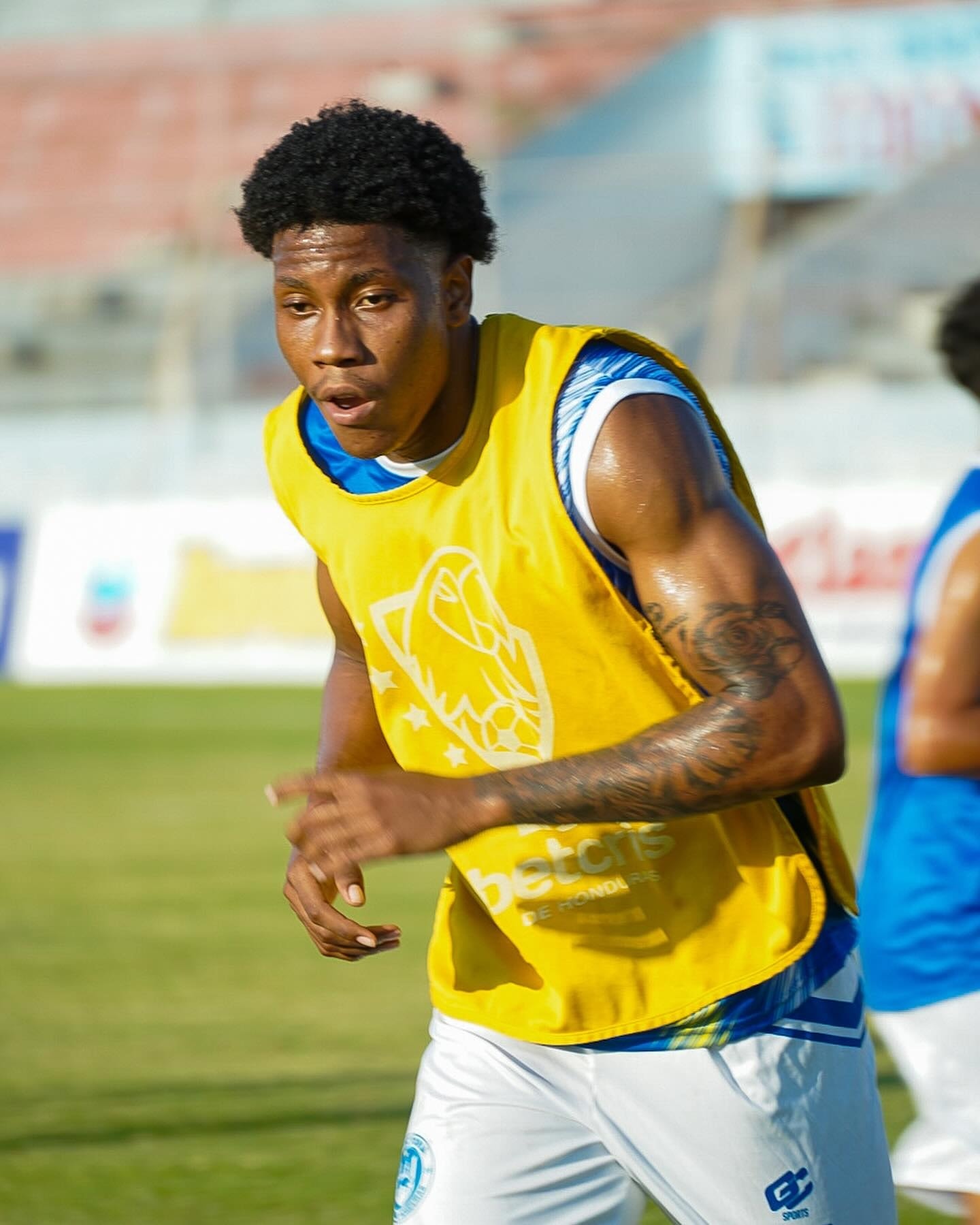 Jugador corriendo con peto amarillo en el entrenamiento
