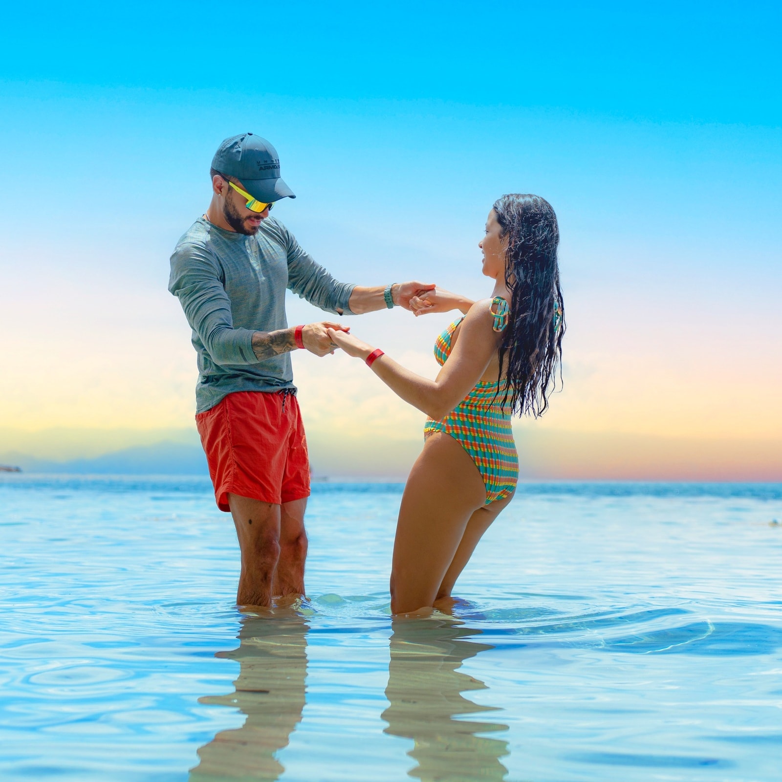 Pareja bailando dentro del mar frente a la playa del hotel