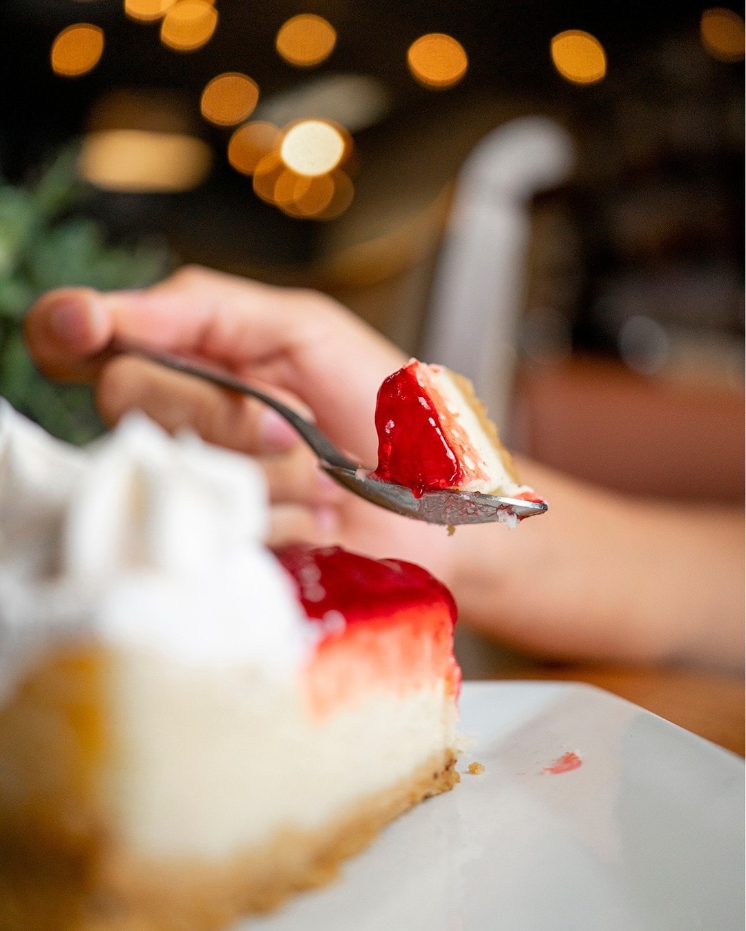 Cuchara partiendo una porción de cheesecake de fresa