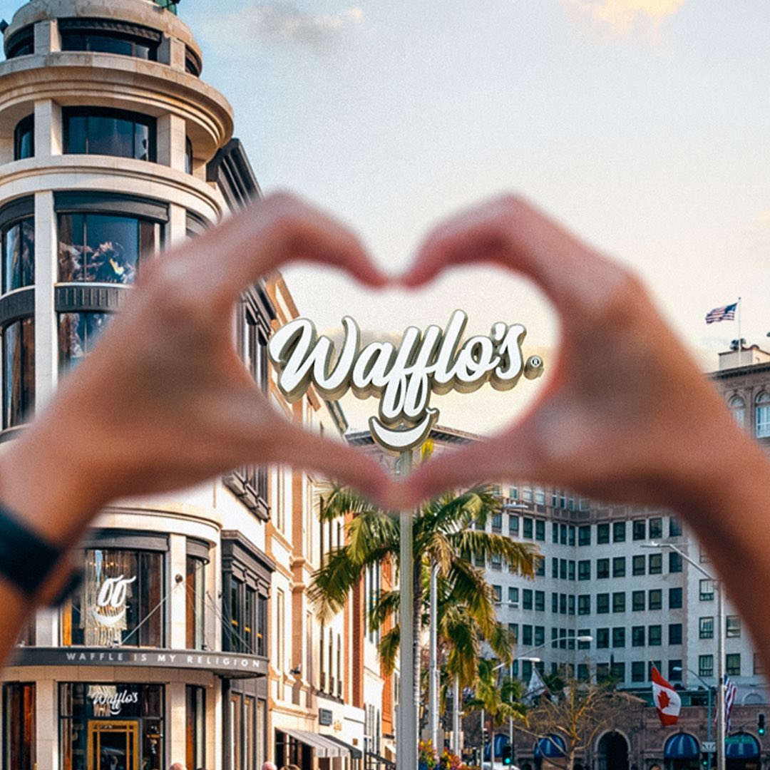 Manos formando un corazón frente al rótulo de Waffl's
