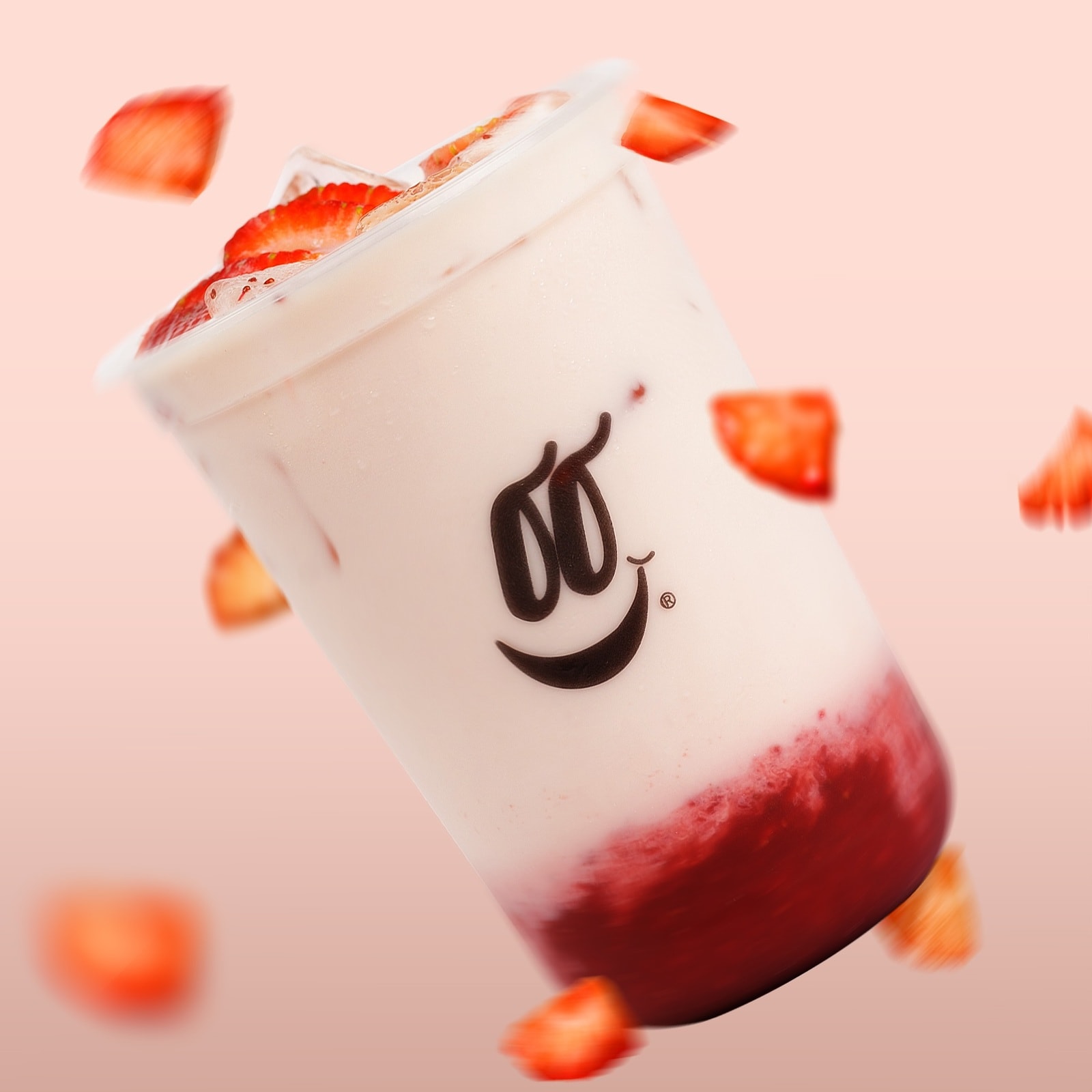 Bebida de fresa con trozos de fruta cayendo alrededor