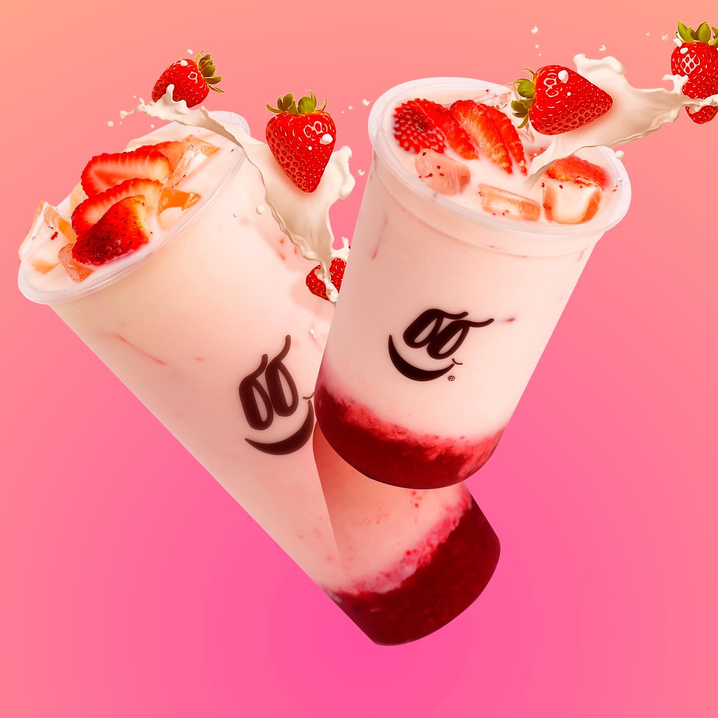 Dos bebidas de fresa flotando sobre fondo rosa